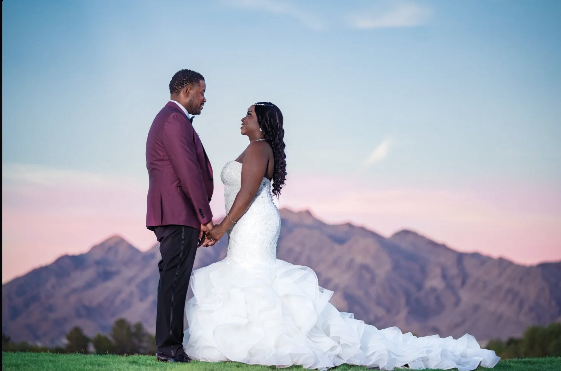 Las Vegas wedding photography — bride and groom holding hands at sunset with the desert mountains behind them